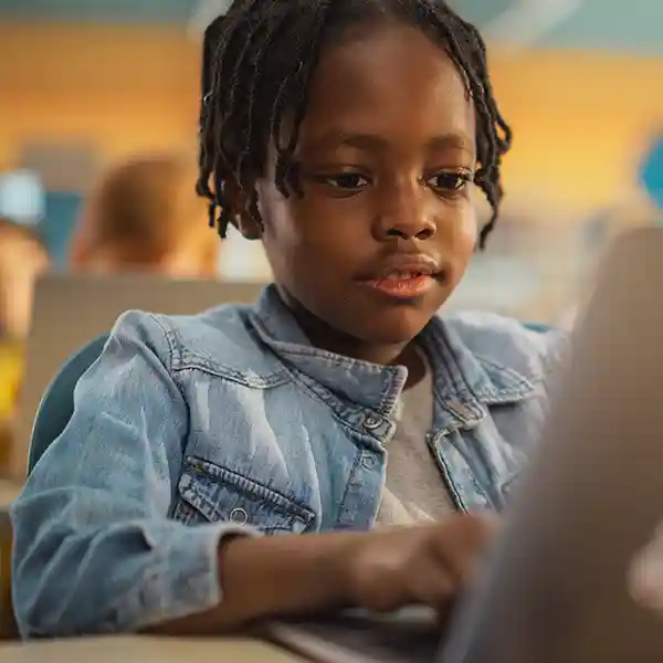 Person smiling and giving a thumbs-up while working on a laptop in a home office.